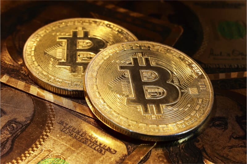 Goldene Bitcoins mit Dollarscheine im Hintergrund