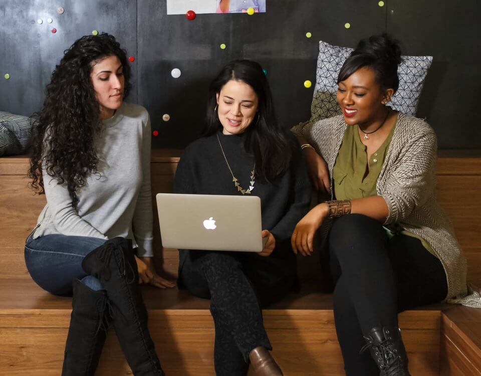 Drei Frauen vor einem Macbook