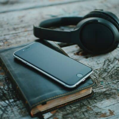 Schwarze Kopfhörer neben Handy auf Notizblock